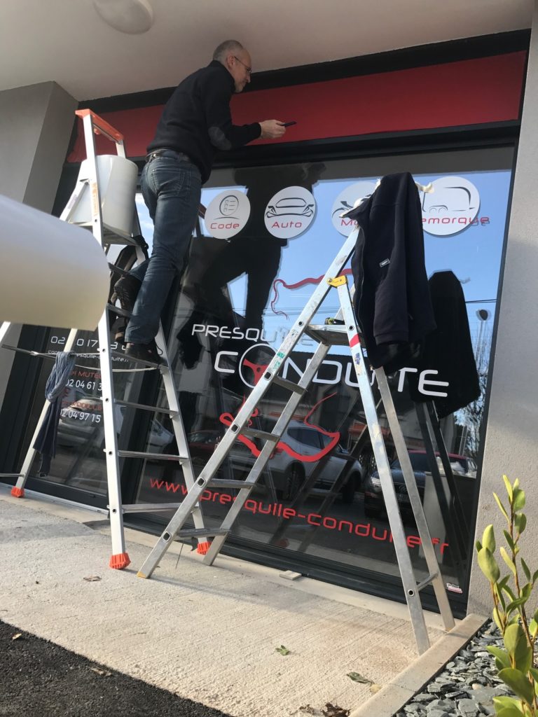 Pose de vitrine sur l'enseigne presqu'il conduite